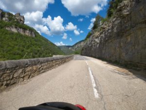 Panoramastraße gesäumt von felsigen Klippen und grünen Hügeln, ideal für geführte Motorradtouren unter blauem Himmel.