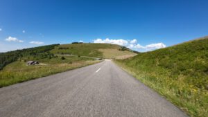 Eine asphaltierte Straße schlängelt sich unter klarem Himmel durch üppige Hügel, perfekt für geführte Motorradtouren.