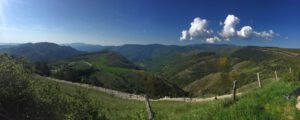 Ein üppiges Tal mit gewundenen Pfaden, ideal für geführte Motorradtouren unter einem klaren blauen Himmel.