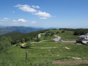 Eine kurvenreiche Straße durch üppige Felder und Berge lädt zu geführten Motorradreisen unter einem klaren blauen Himmel ein.