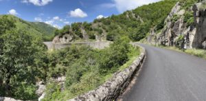 Eine glatte Asphaltstraße schlängelt sich durch üppiges Grün, ideal für geführte Motorradtouren zwischen Klippen und Bäumen.