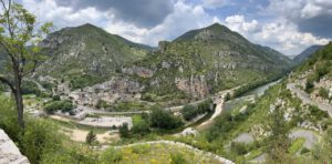 Eine üppige Berglandschaft mit Dorf und Fluss, perfekt für geführte Motorradtouren.