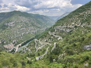 Eine malerische kurvenreiche Straße für geführte Motorradtouren schlängelt sich durch üppige Berge bei bewölktem Himmel.