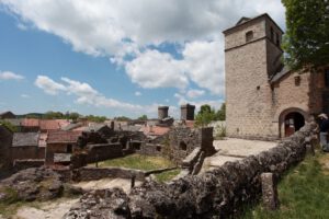 Mit Blick auf ein Dorf mit roten Dächern, einer mittelalterlichen Burg und antiken Ruinen laden malerische Motorradtouren ein.