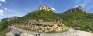 Eine kurvenreiche Straße inmitten üppigen Grüns und felsiger Klippen ist perfekt für geführte Motorradtouren.