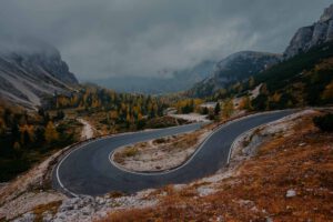 Eine kurvenreiche Bergstraße mit Herbstnebel bietet eine stimmungsvolle Kulisse für geführte Motorradtouren.