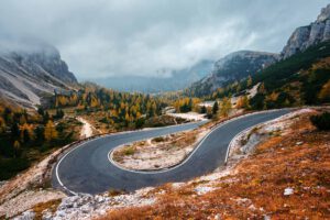 Eine malerische Bergstraße schlängelt sich zwischen leuchtenden Herbstbäumen hindurch und eignet sich perfekt für geführte Motorradtouren.