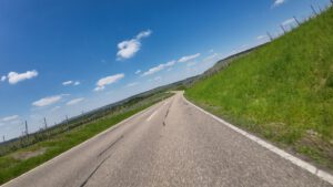 Eine kurvenreiche Straße führt durch eine lebendige Landschaft, perfekt für geführte Motorradtouren unter blauem Himmel.