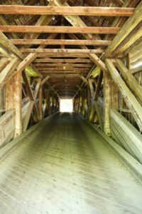Fahren Sie auf unserer Tour durch einen hölzernen Brückentunnel, dessen komplizierte Balken vom Sonnenlicht beleuchtet werden.