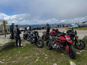 Motorradfahrer entspannen an einem malerischen Bergaussichtspunkt und genießen die Kameradschaft an einem bewölkten Tag.