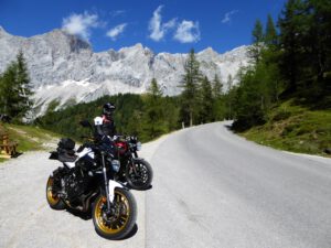Zwei Motorradfahrer genießen eine malerische Bergstraße, perfekt für unvergessliche geführte Motorradreisen.