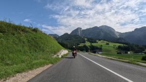 Ein Motorradfahrer fährt auf einer geführten Motorradreise eine malerische Bergstraße inmitten üppiger Hügel und Berge entlang.