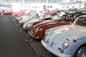 Oldtimer-Sportwagen werden im Innenbereich elegant präsentiert, jeder mit einem aussagekräftigen Schild und einem lebendigen Design.