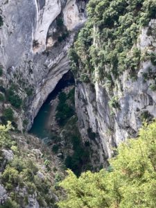 Üppige, steile Kalksteinfelsen ragen über eine schattige Schlucht empor, durch die sich ein gewundener Fluss schlängelt.