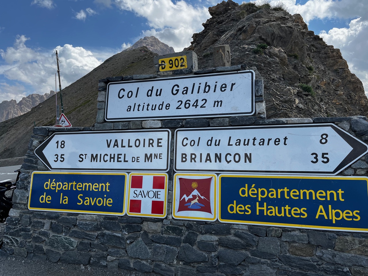 IMG_7549 Verkehrsschilder am Col du Galibier (2642 m) in den Alpen weisen den Weg zu den umliegenden Ortschaften vor einer Bergkulisse.